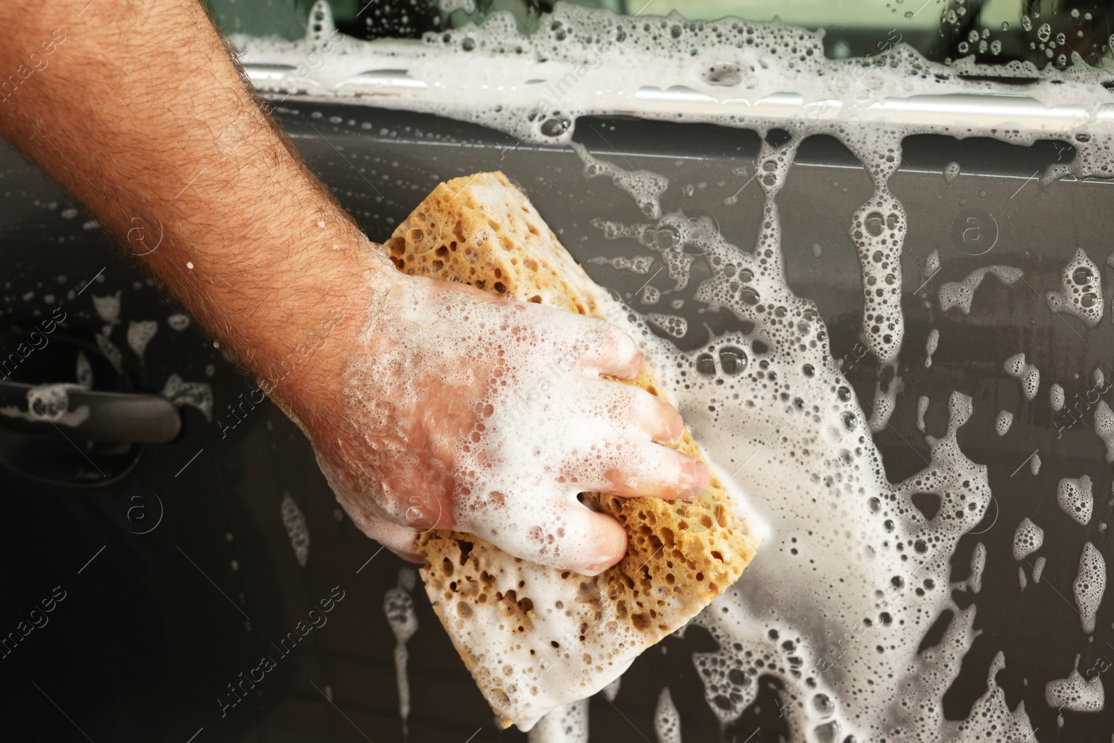 Photo of Man washing auto with sponge at car wash, closeup