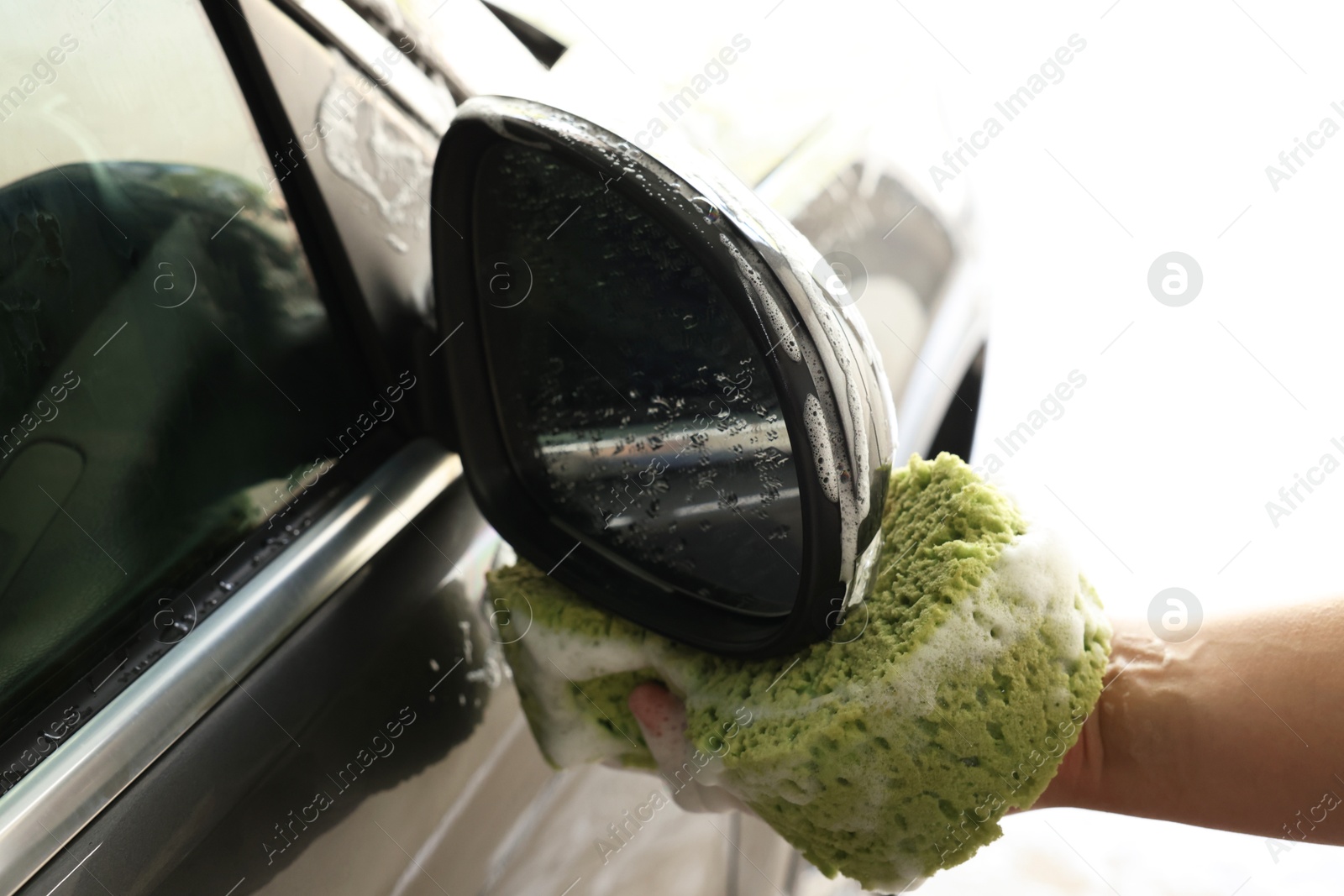 Photo of Man washing auto with sponge at car wash, closeup