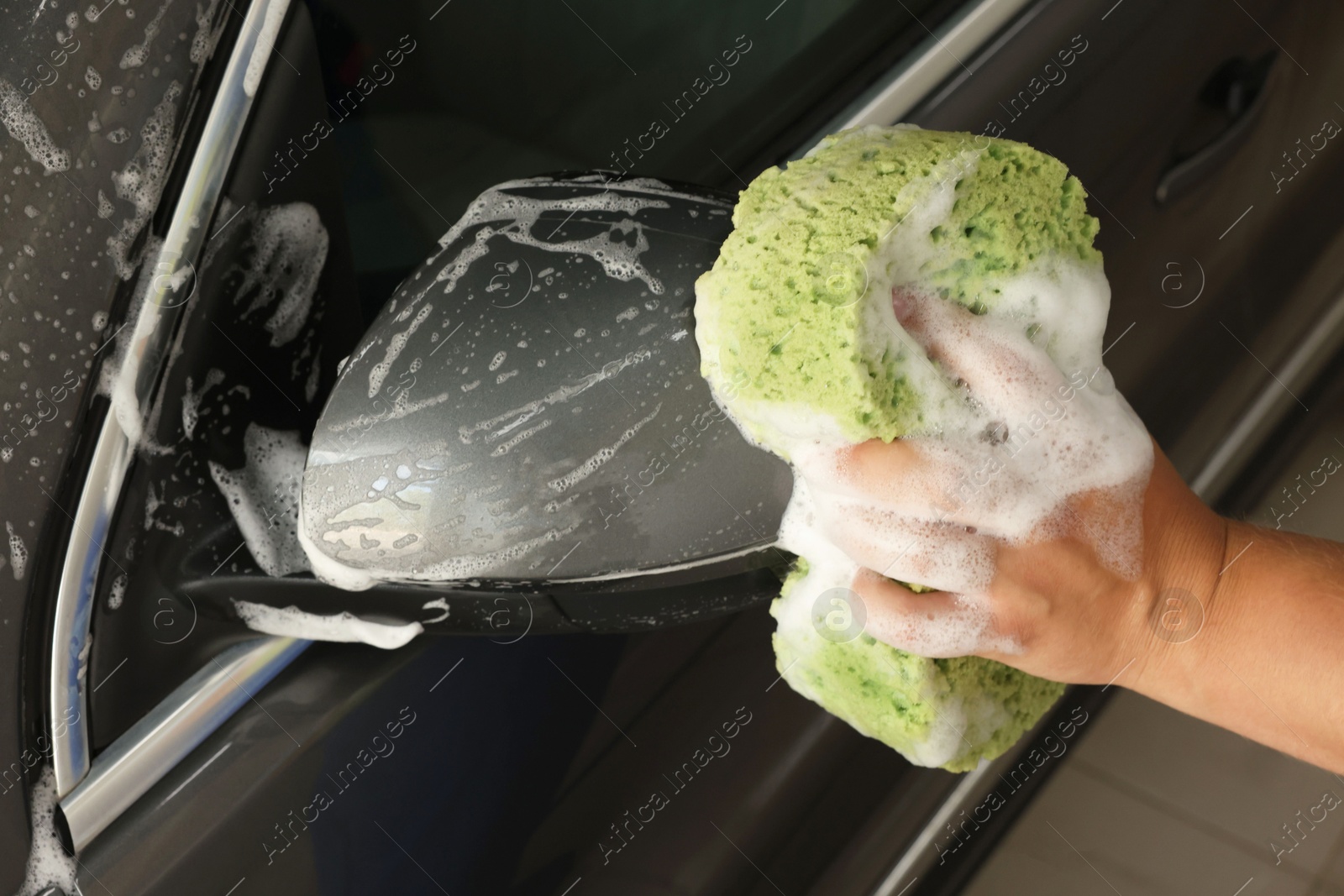 Photo of Man washing auto with sponge at car wash, closeup