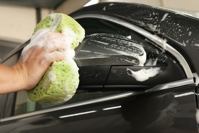 Photo of Man washing auto with sponge at car wash, closeup