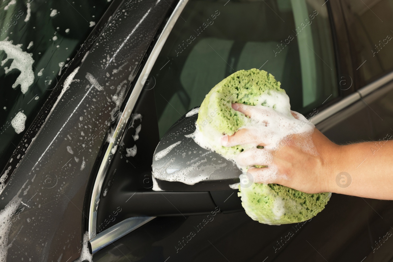 Photo of Man washing auto with sponge at car wash, closeup