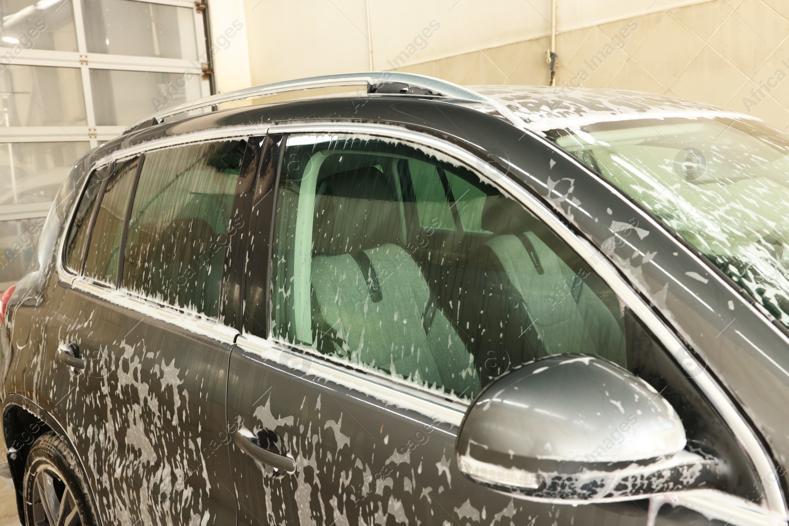 Photo of Auto covered with cleaning foam at car wash, closeup