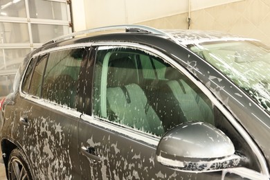 Auto covered with cleaning foam at car wash, closeup