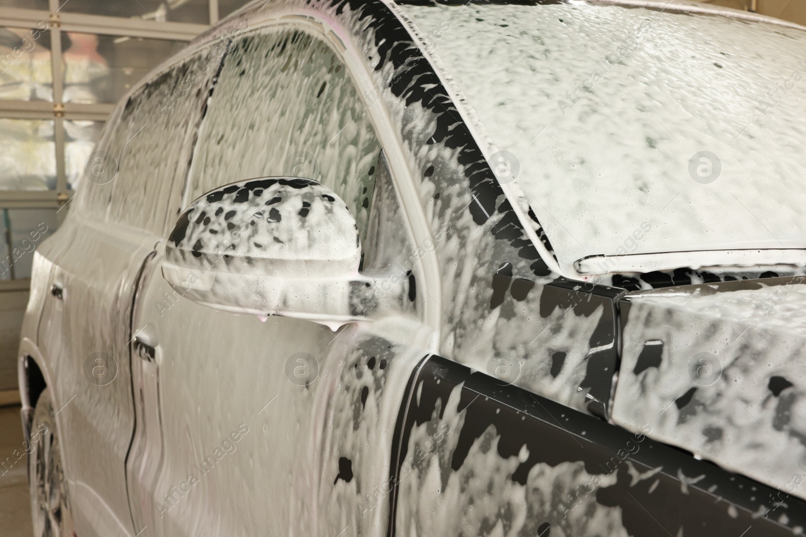 Photo of Auto covered with cleaning foam at car wash, closeup