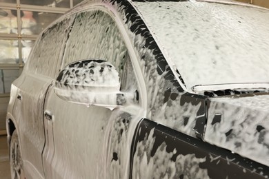 Auto covered with cleaning foam at car wash, closeup