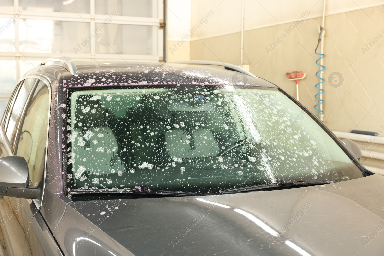 Photo of Auto covered with cleaning foam at car wash, closeup