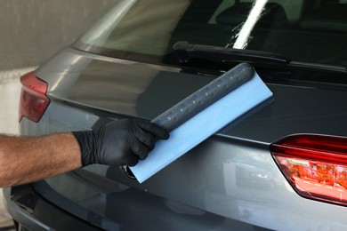 Photo of Man wiping auto with squeegee brush at car wash, closeup