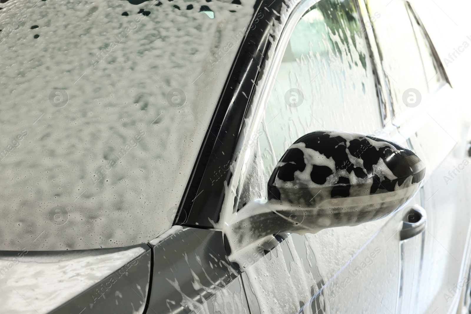 Photo of Auto covered with cleaning foam at car wash, closeup