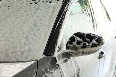 Auto covered with cleaning foam at car wash, closeup