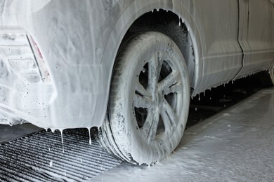 Auto covered with cleaning foam at car wash, closeup