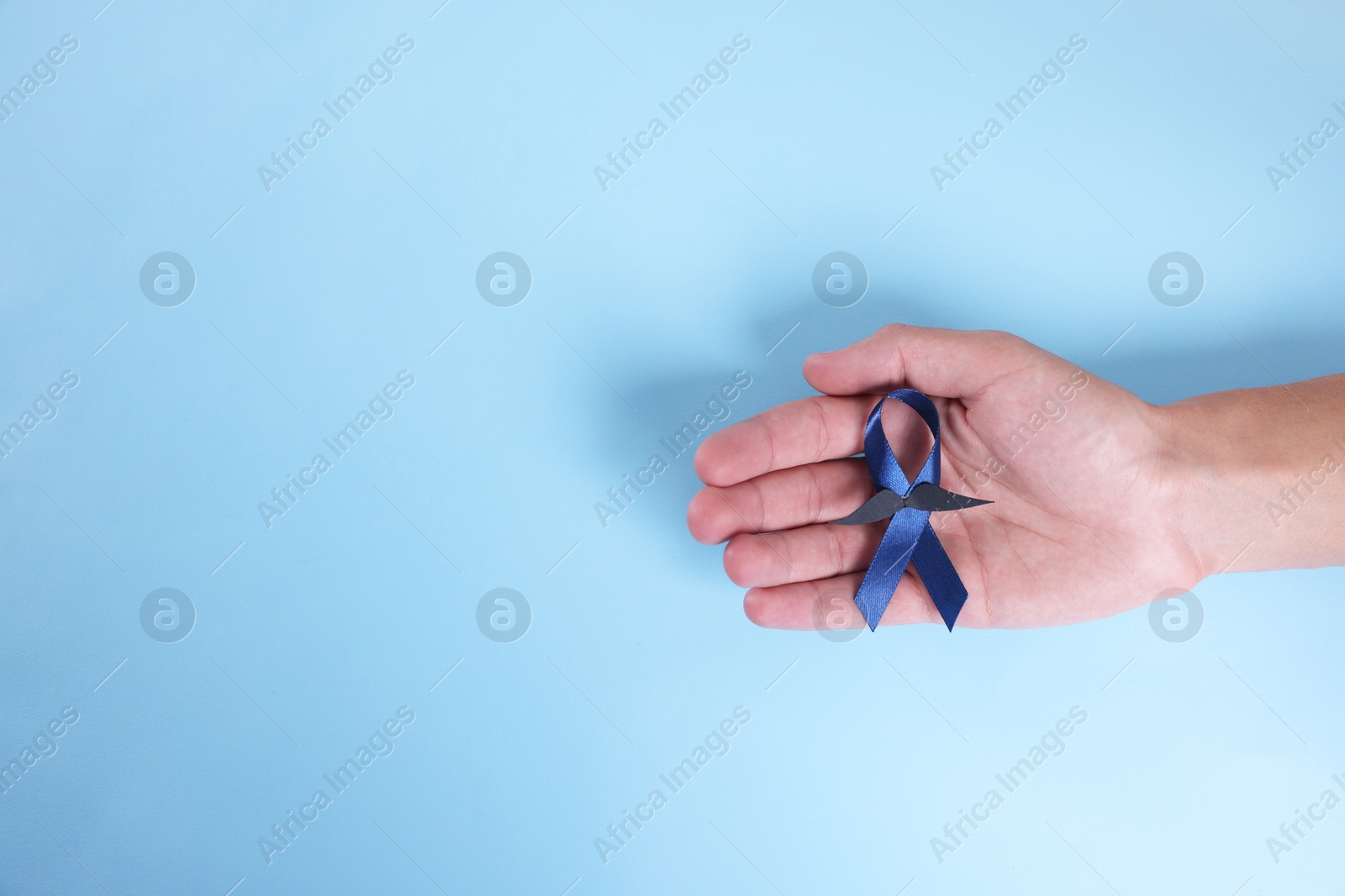 Photo of Prostate cancer awareness. Man with light blue ribbon as symbol of support on color background, top view. Space for text