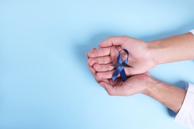 Photo of Prostate cancer awareness. Man with light blue ribbon as symbol of support on color background, top view. Space for text