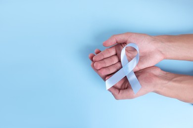 Prostate cancer awareness. Man with light blue ribbon as symbol of support on color background, top view. Space for text