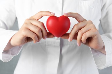 Photo of Doctor holding red heart on grey background, closeup