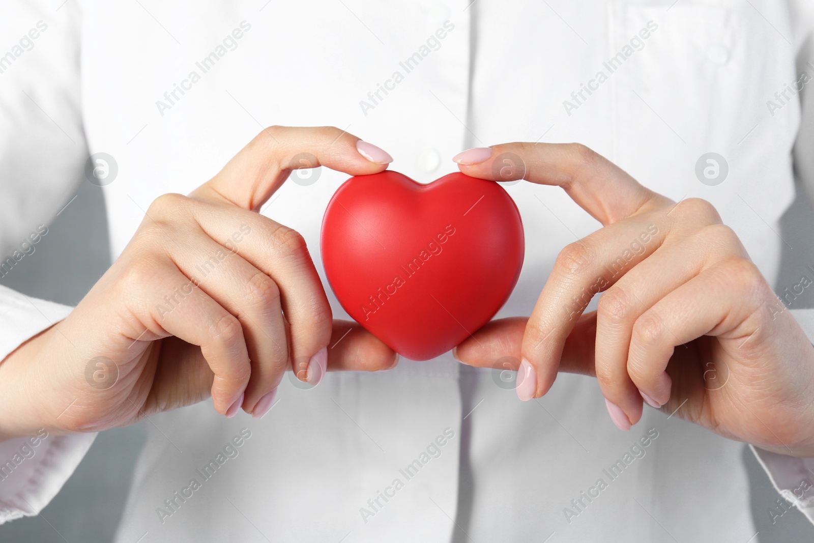 Photo of Doctor holding red heart on grey background, closeup