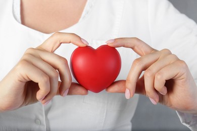 Photo of Doctor holding red heart on grey background, closeup