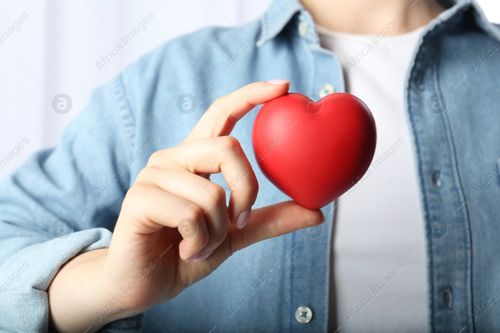 Photo of Woman holding red heart on light background, closeup