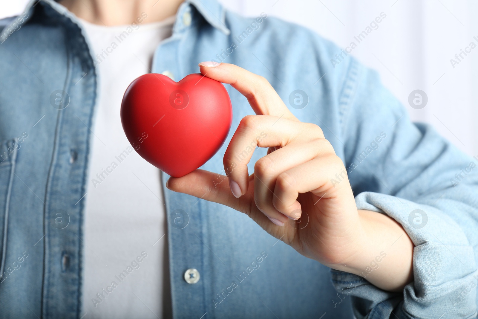 Photo of Woman holding red heart on light background, closeup