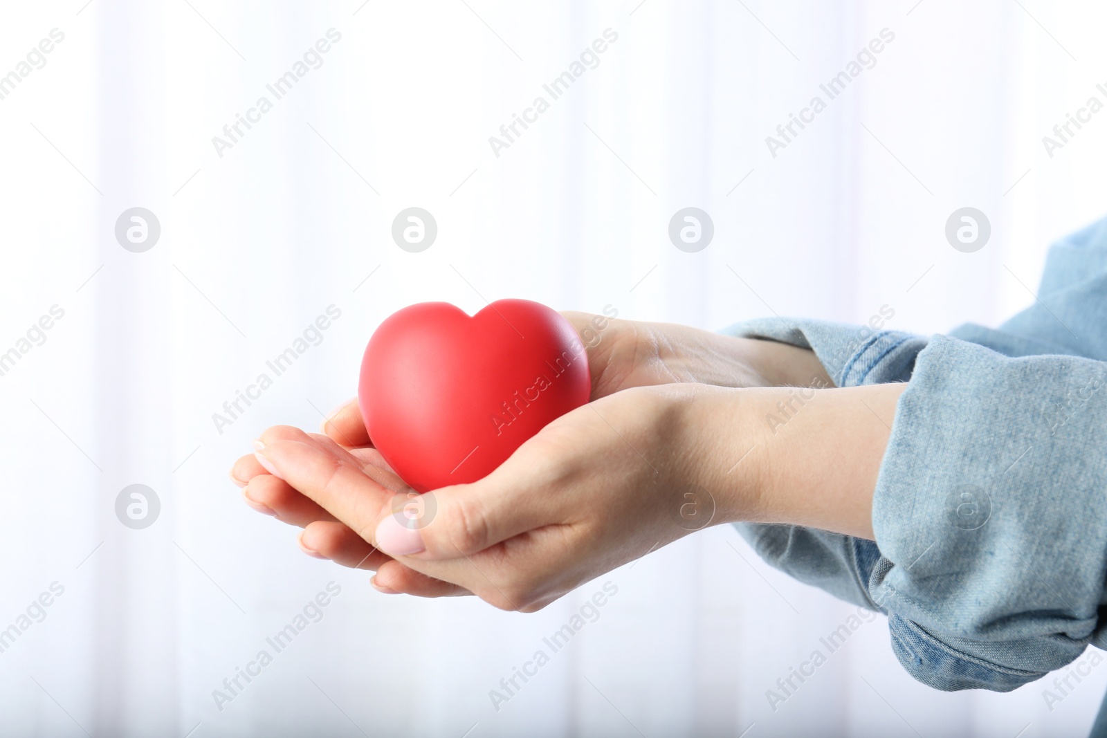 Photo of Woman holding red heart on light background, closeup