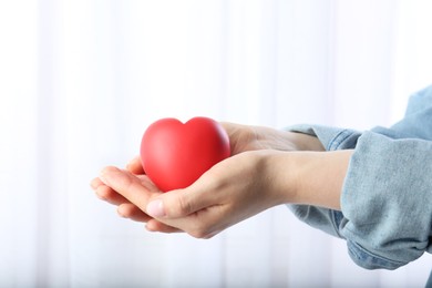 Photo of Woman holding red heart on light background, closeup