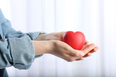 Photo of Woman holding red heart on light background, closeup