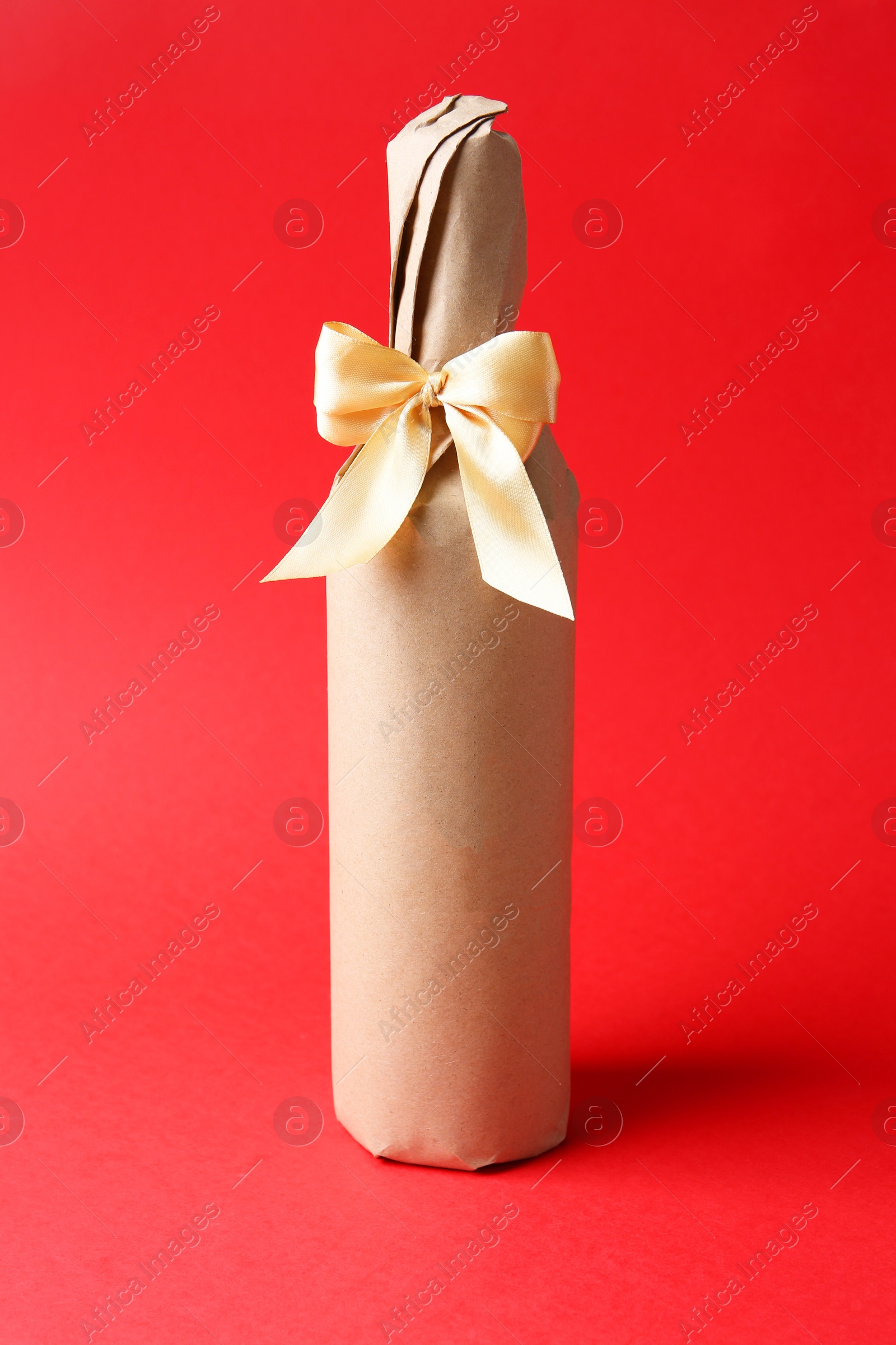 Photo of Wine packed bottle with ribbon on red background