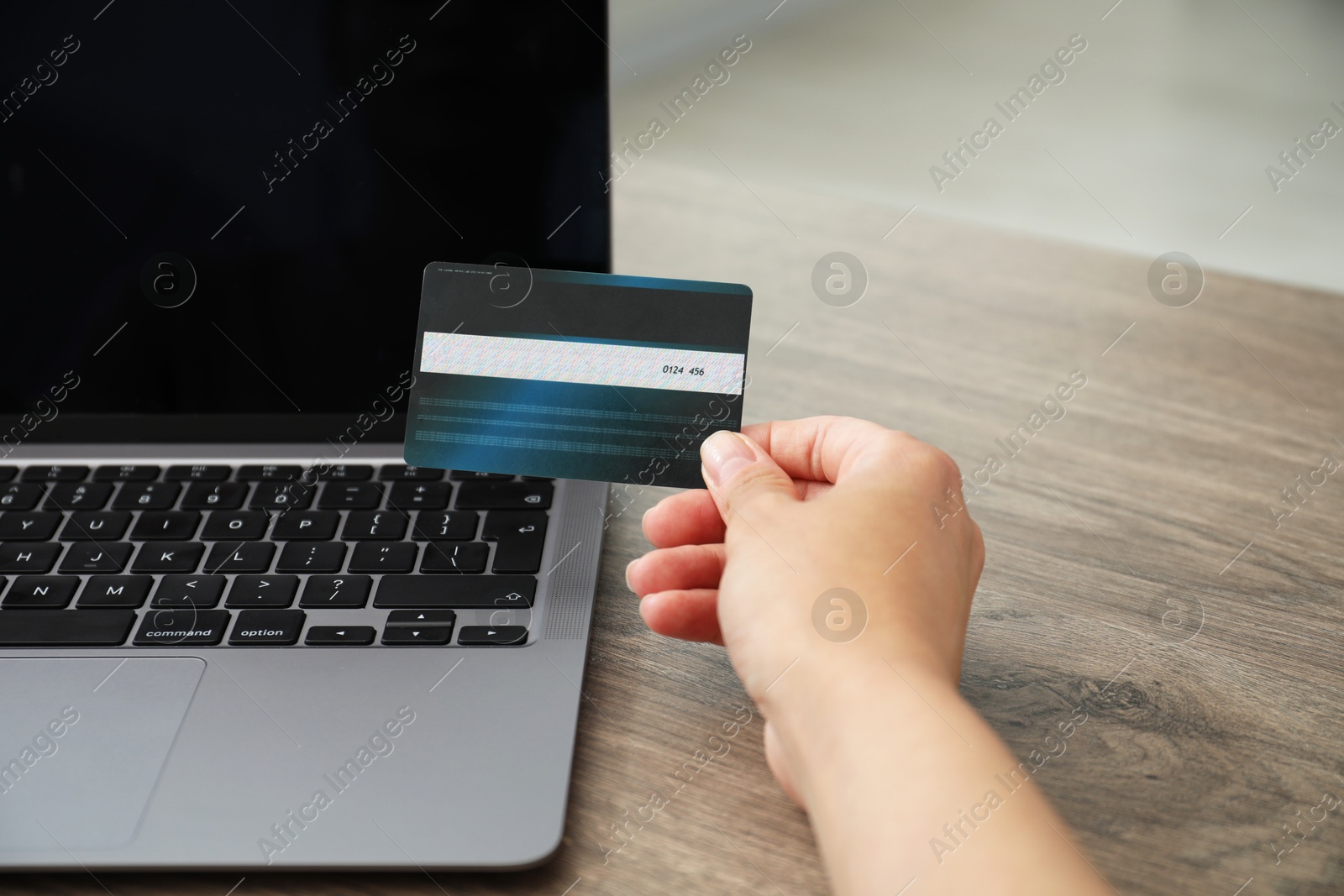 Photo of Woman with credit card using laptop at wooden table indoors, closeup