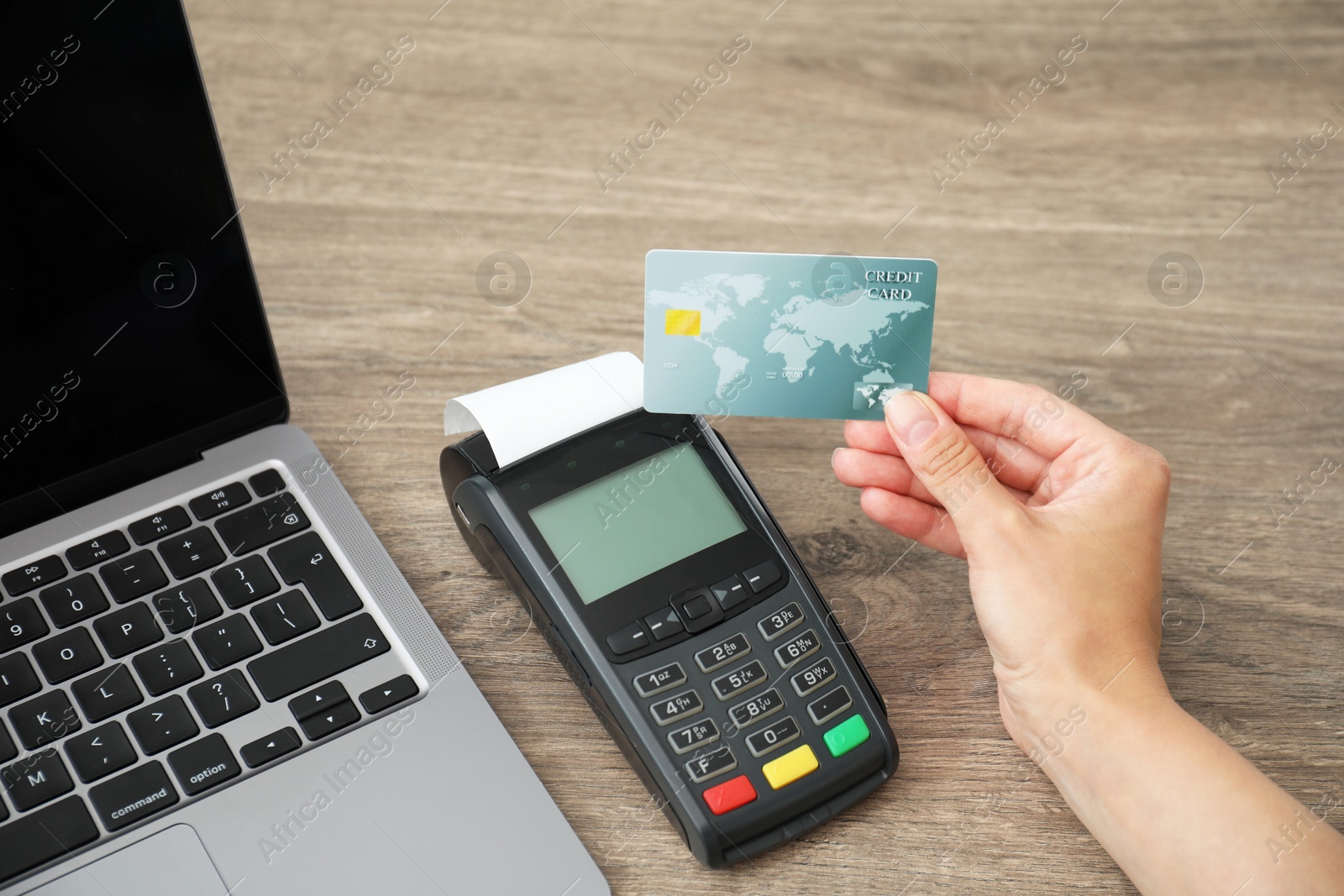 Photo of Woman with credit card using payment terminal at wooden table indoors, closeup