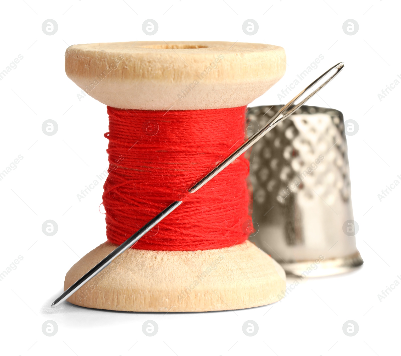 Photo of Thimble and needle with red sewing thread isolated on white, closeup