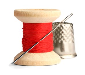 Thimble and needle with red sewing thread isolated on white, closeup