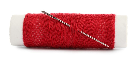 Photo of Spool of red sewing thread with needle isolated on white