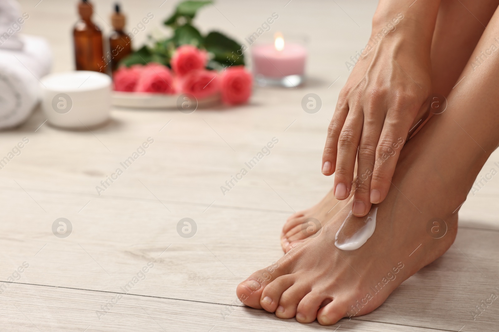 Photo of Body care. Woman applying moisturizing cream onto her feet on floor, closeup. Space for text