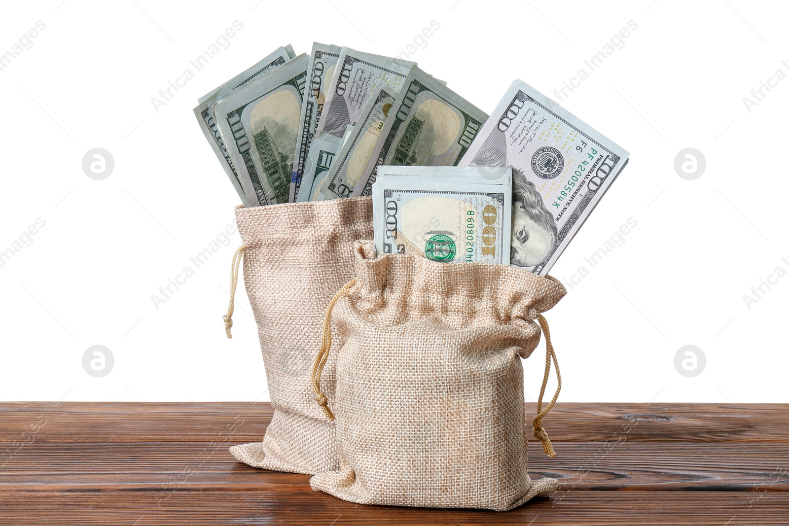 Photo of Dollar banknotes in bags on wooden table against white background