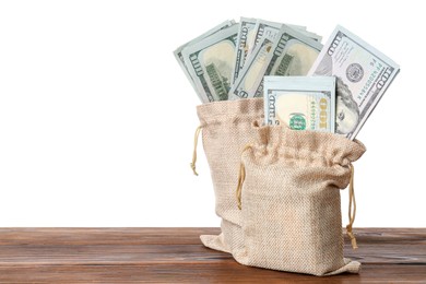 Photo of Dollar banknotes in bags on wooden table against white background, space for text