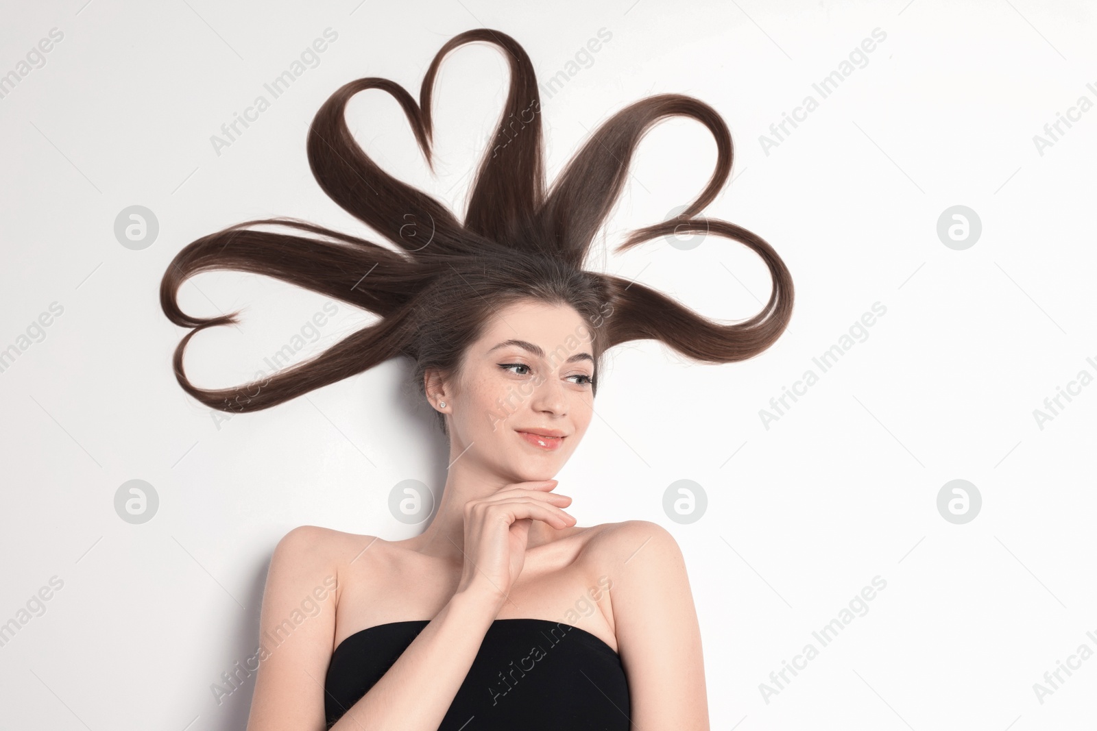 Photo of Beautiful young woman with hair in shape of hearts on white background, top view