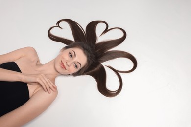 Beautiful young woman with hair in shape of hearts on white background