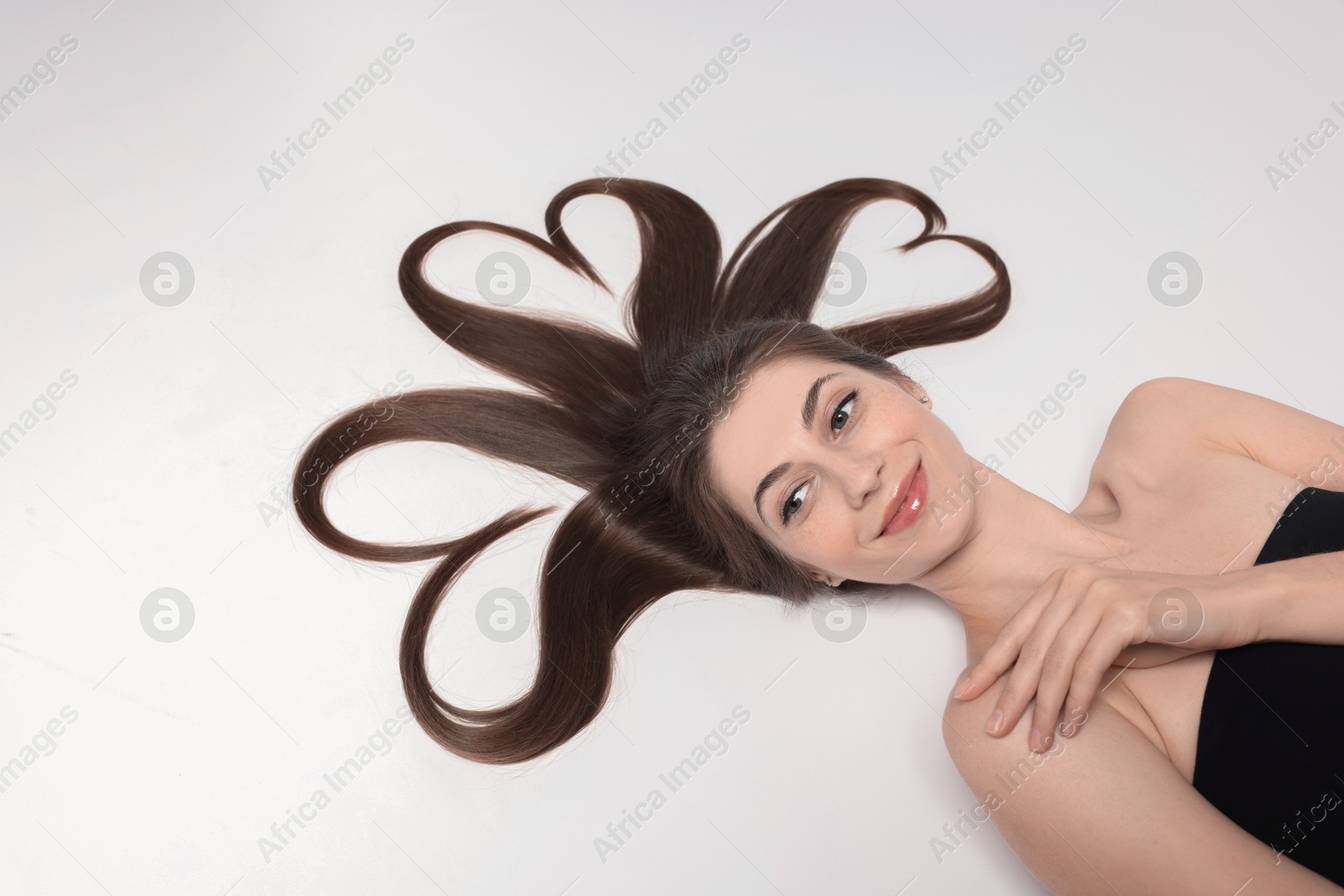 Photo of Beautiful young woman with hair in shape of hearts on white background