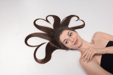 Photo of Beautiful young woman with hair in shape of hearts on white background