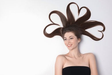 Photo of Beautiful young woman with hair in shape of hearts on white background, top view. Space for text