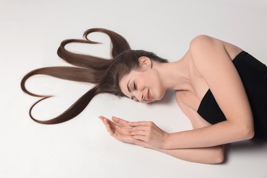 Photo of Beautiful young woman with hair in shape of hearts on white background