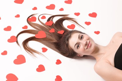 Photo of Beautiful young woman with long hair and red paper hearts on white background