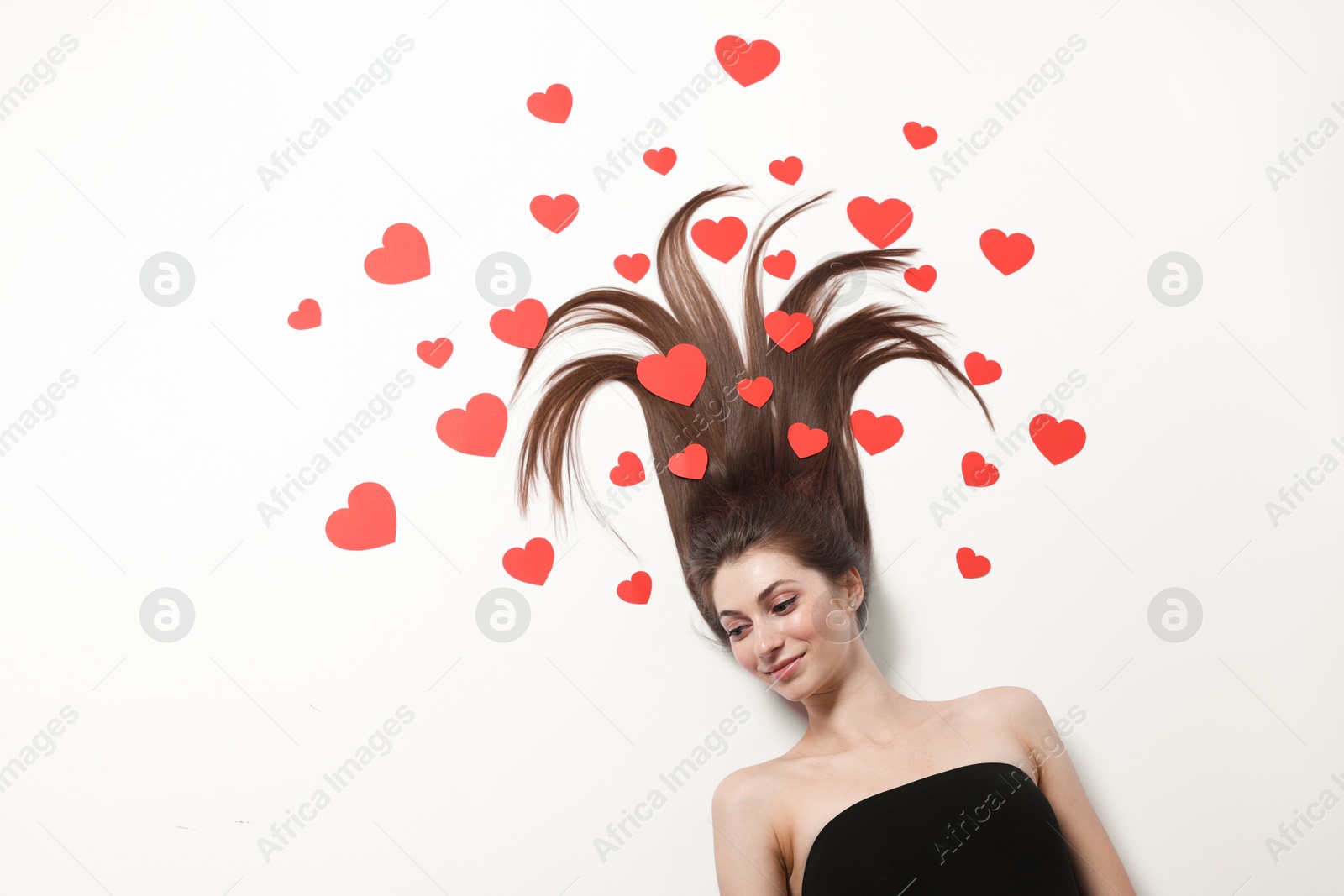 Photo of Beautiful young woman with long hair and red paper hearts on white background, top view