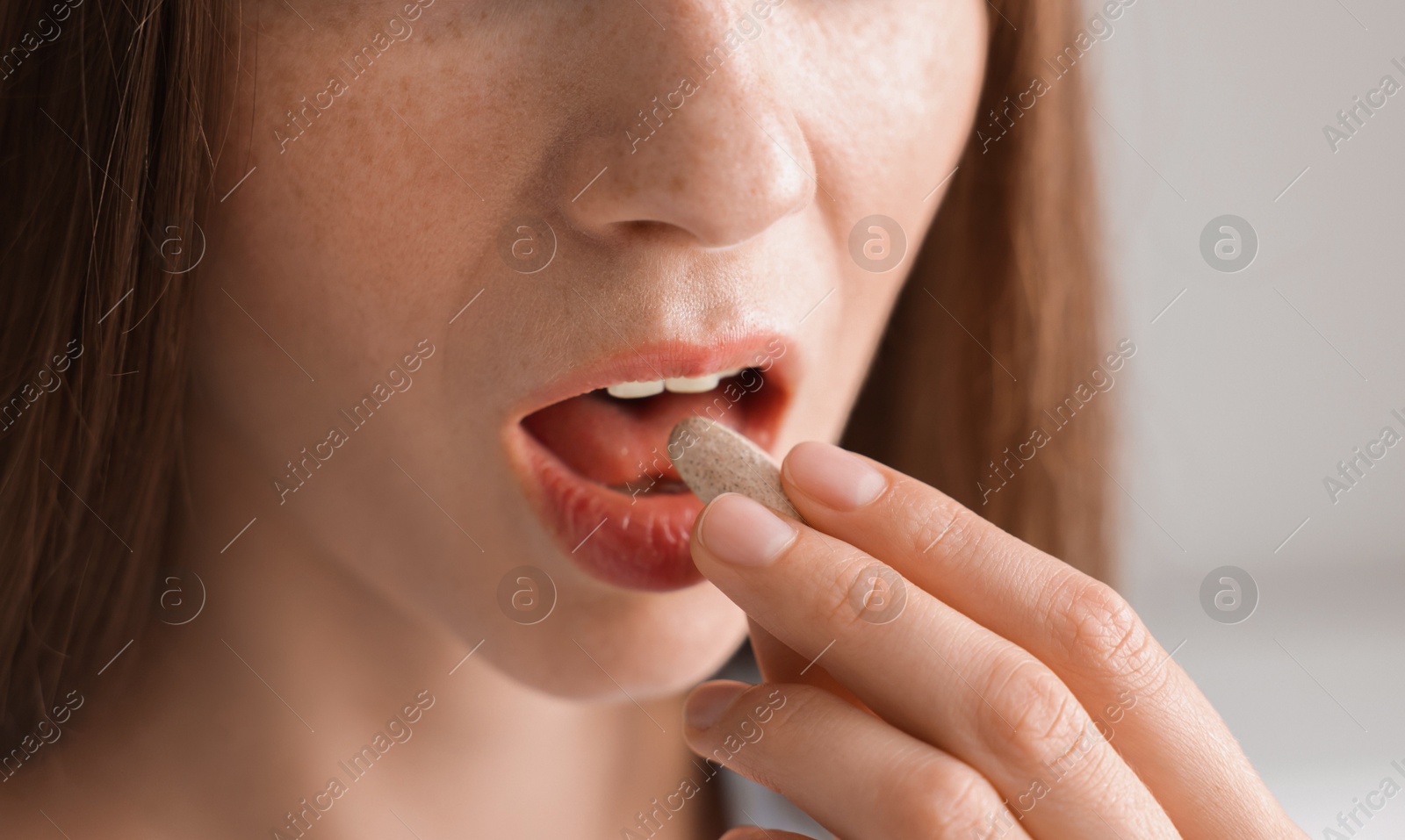 Photo of Woman taking pill on blurred background, closeup