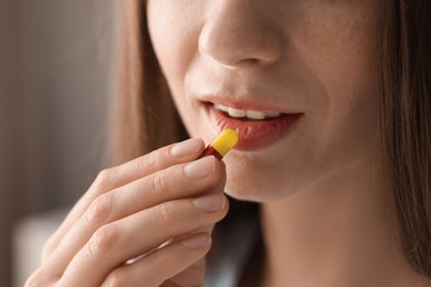 Photo of Woman taking pill on blurred background, closeup