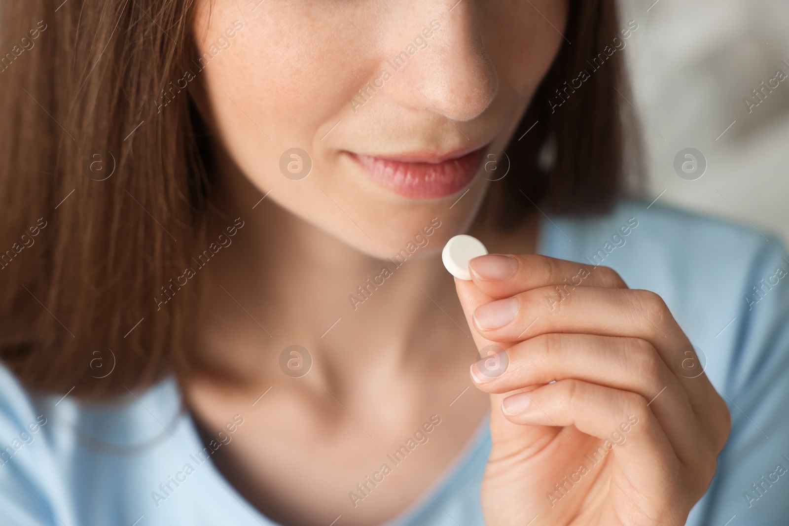 Photo of Woman taking pill on blurred background, closeup