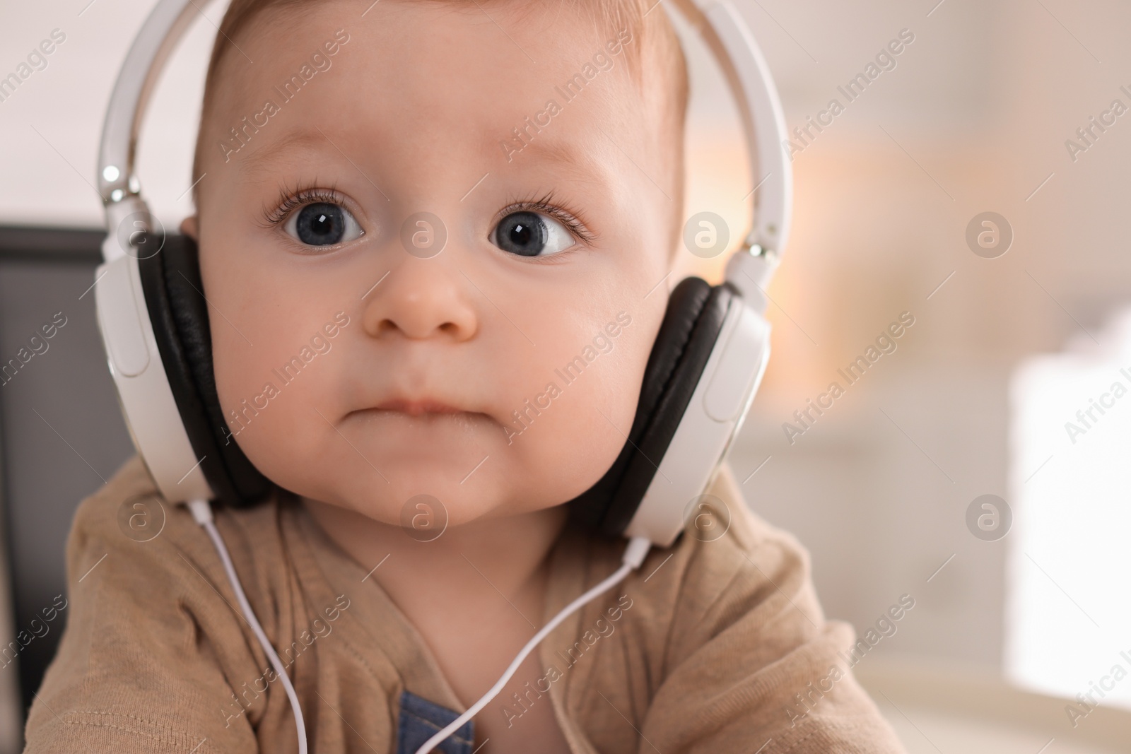 Photo of Cute little baby with headphones at home