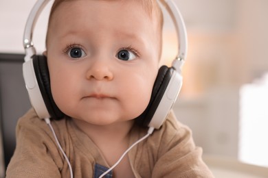 Photo of Cute little baby with headphones at home