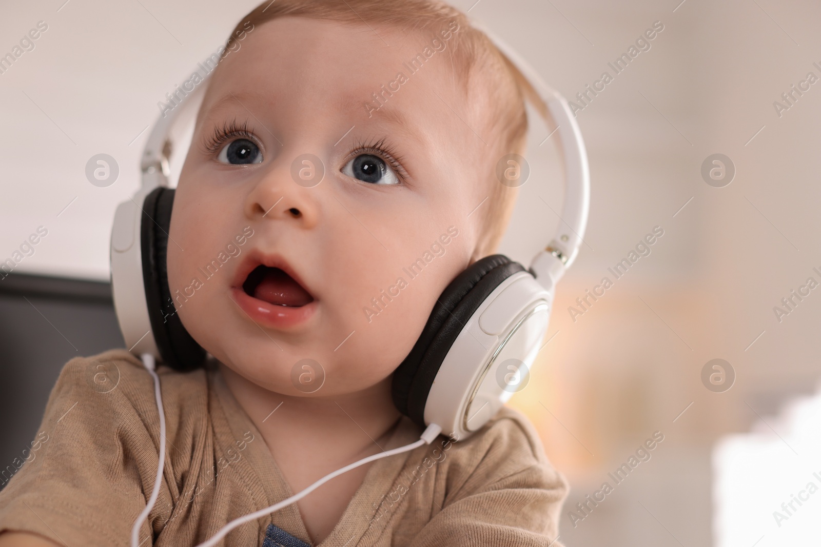 Photo of Cute little baby with headphones at home