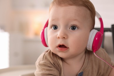 Photo of Cute little baby with headphones at home, space for text