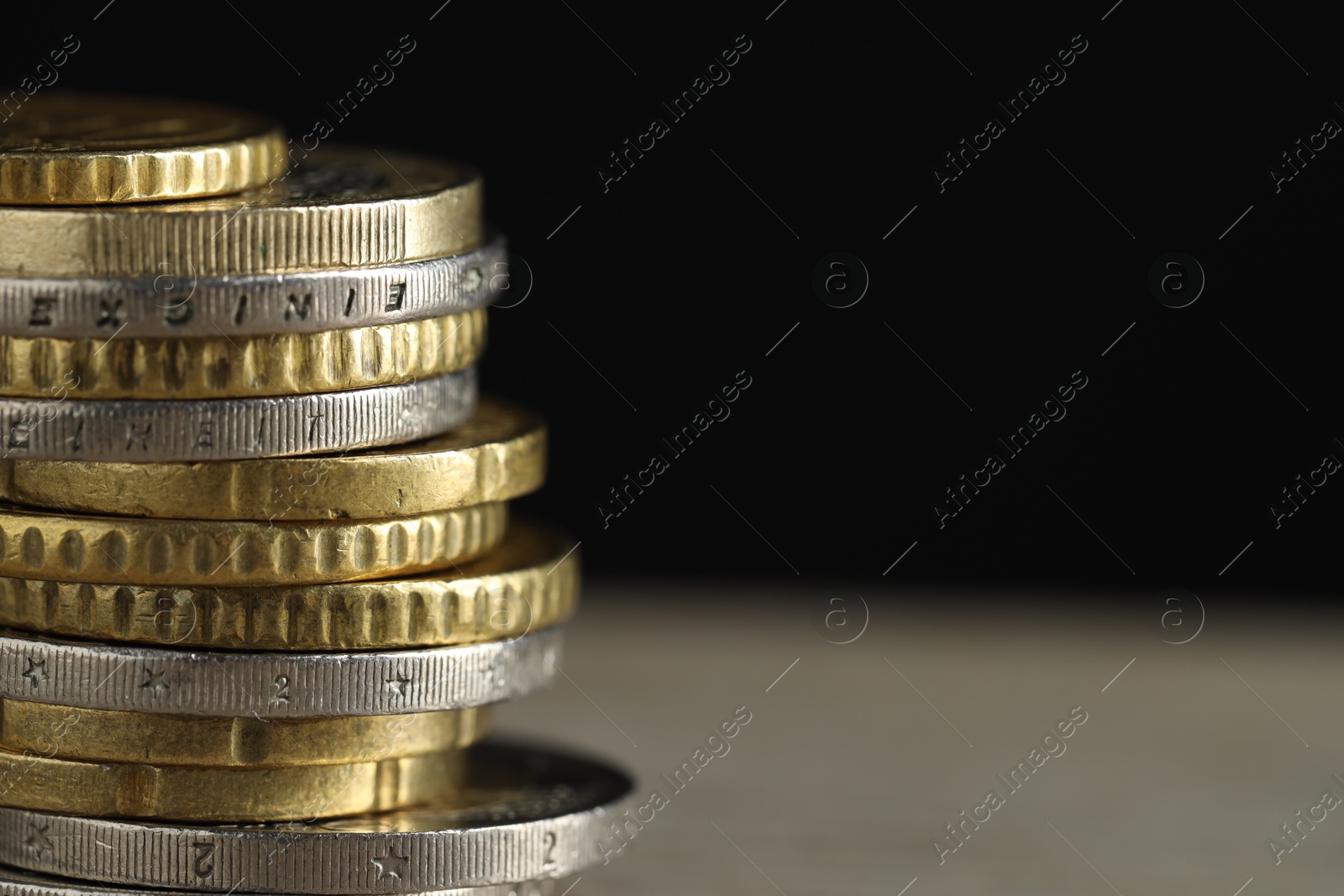 Photo of Stack of coins on table against black background, closeup with space for text. Salary concept